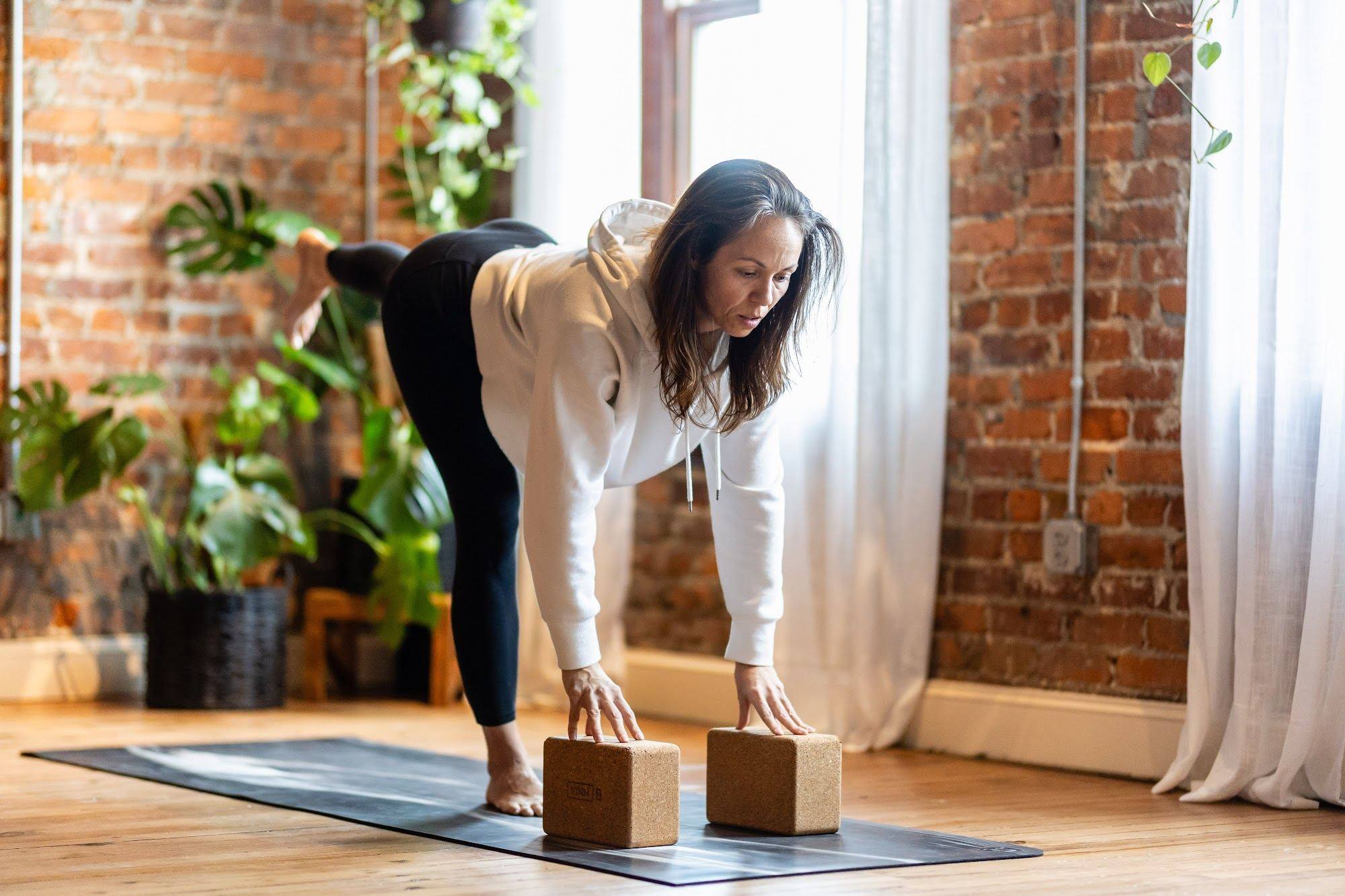 A teacher guiding a student into a forward fold with blocks