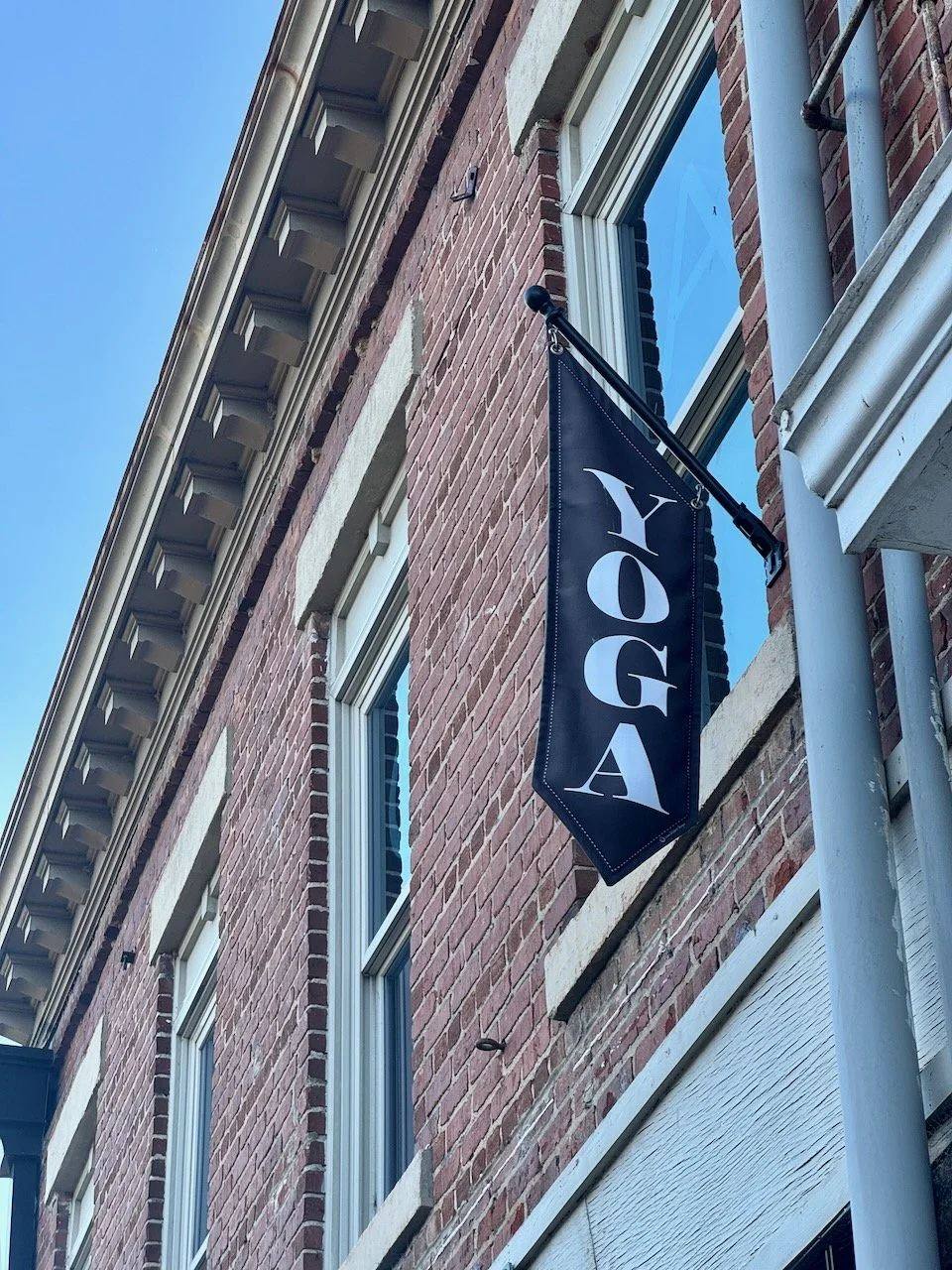 The black YOGA flag outside the brick building on White Street