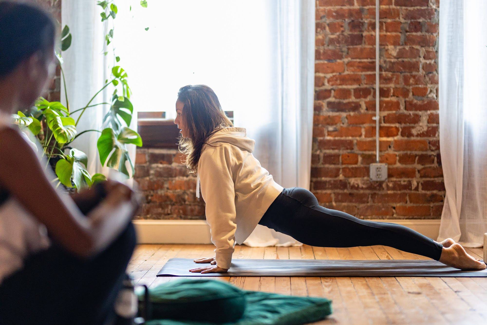 A student holding plank on a mat by the studio window