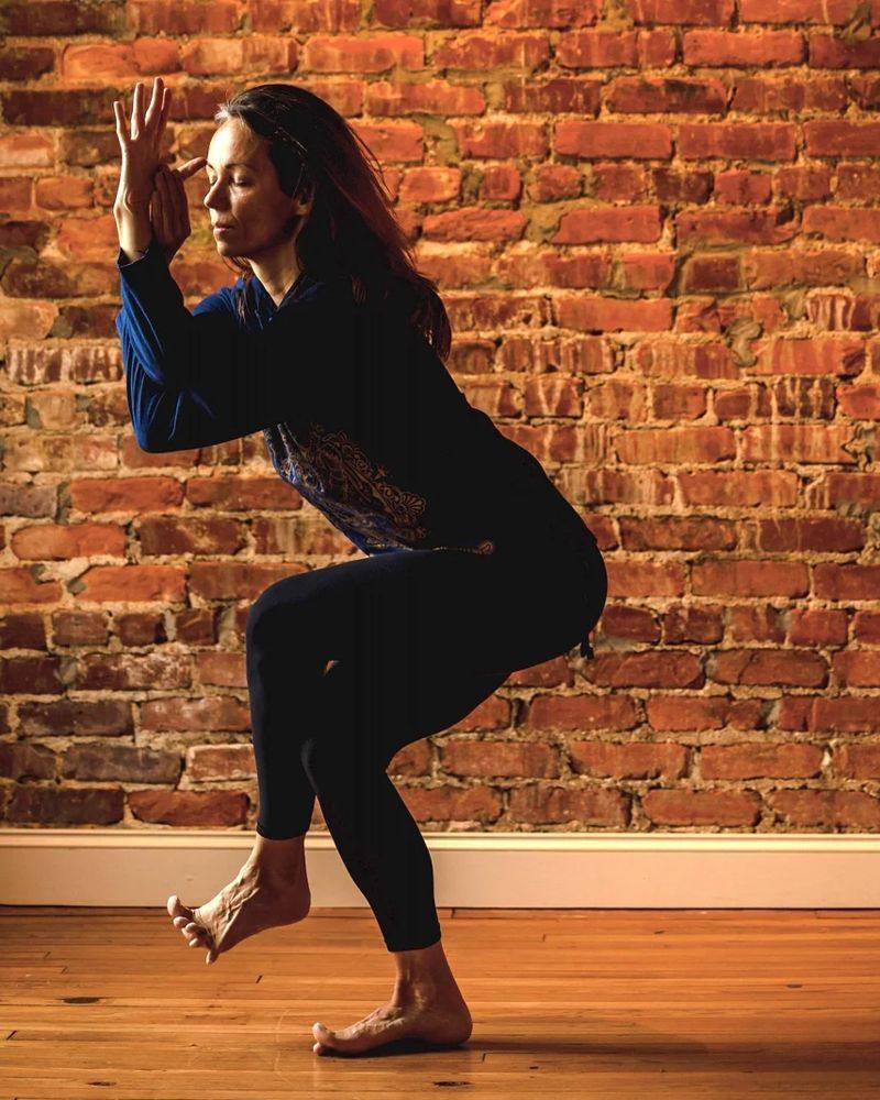 Danielle Forghetti in a balancing pose against the brick wall at The Yoga Loft in Wake Forest