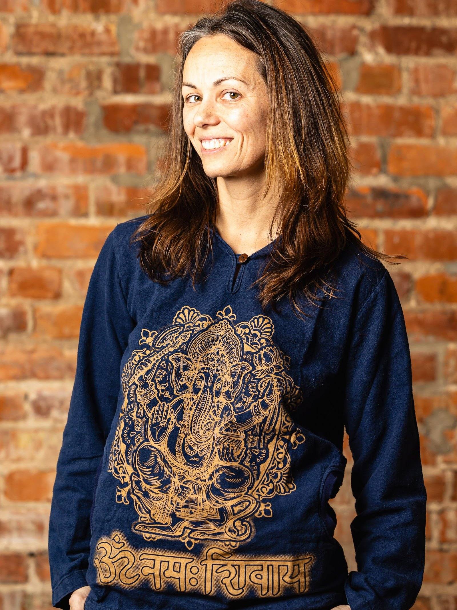 Danielle Forghetti, co-lead trainer, smiling in the brick studio at The Yoga Loft