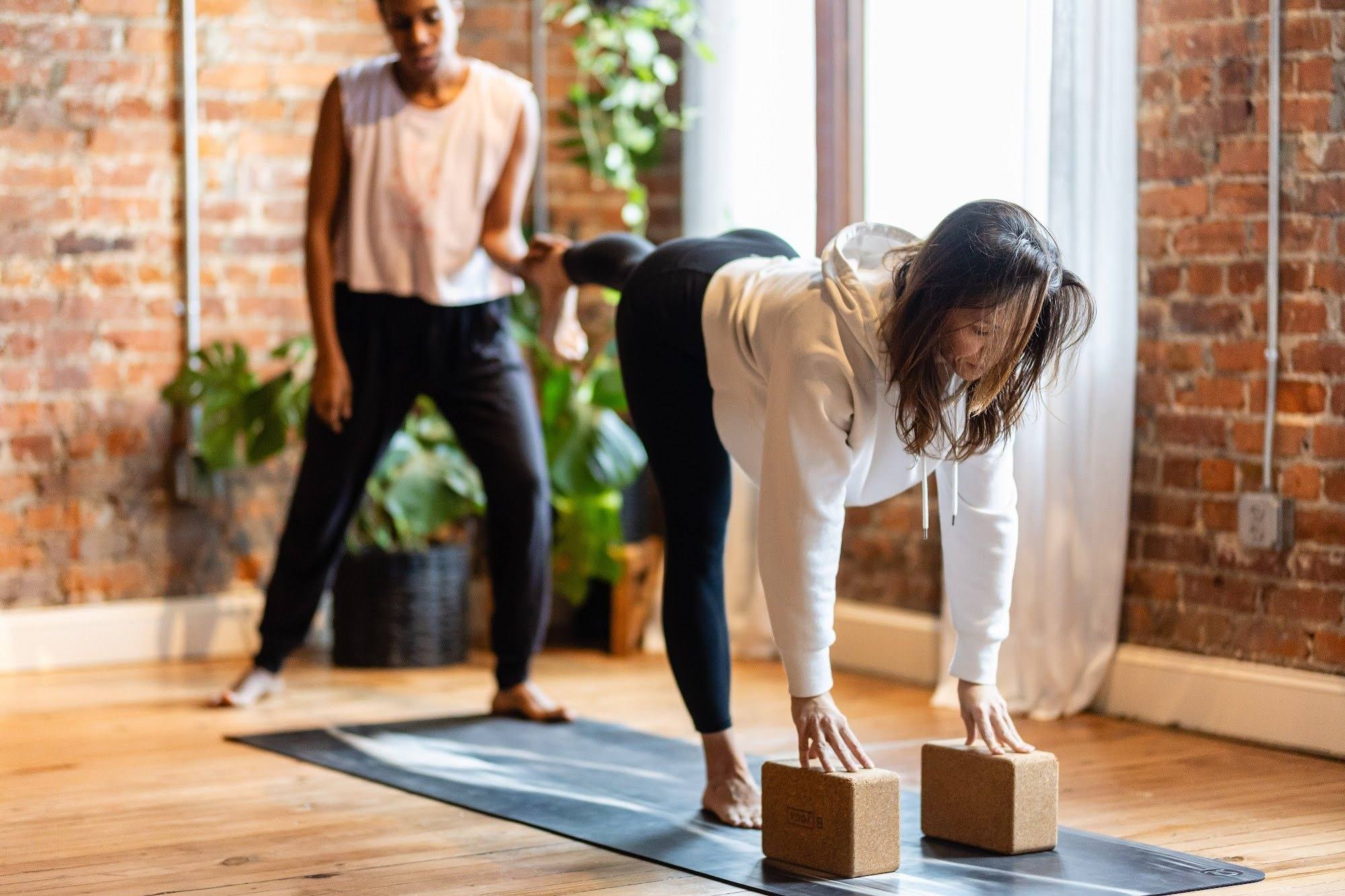 Nicole Bayer guiding Danielle Forghetti into a forward fold at the blocks in the brick studio