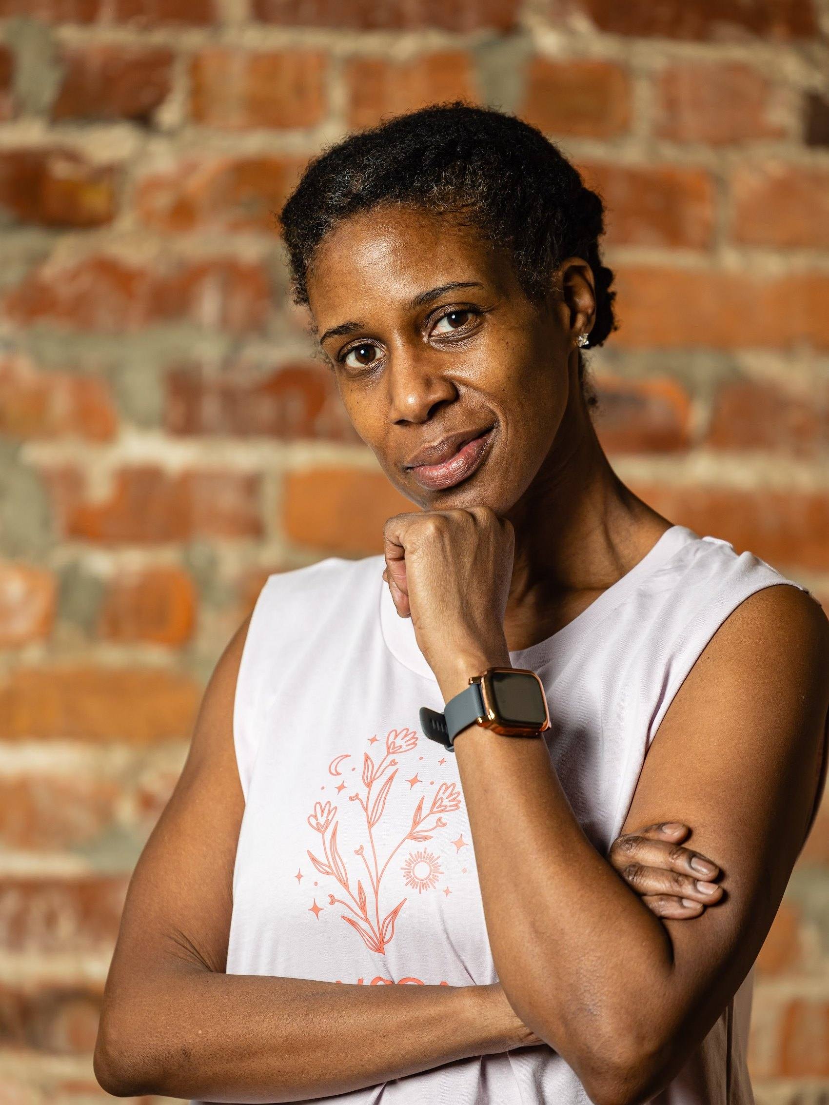 Nicole Bayer, lead trainer, against the brick wall at The Yoga Loft